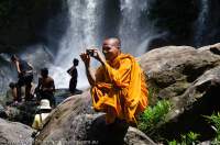 CAMBODIA, Siem Reap. Monk photographing at waterfall, Phnom Kulen.