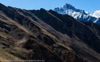 NEPAL, Dolpo. Tilted rock beds and snowy peak, Chhimimaru Khola valley.
