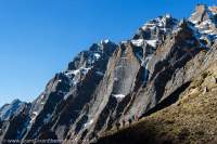 NEPAL, Dolpo. Trekkers below steep limestone bluffs in Swaksa Khola valley.