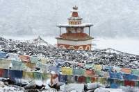 NEPAL, Dolpo. Chortens and mani stone field and Tibetan prayer flags at Shey Gompa (Buddhist), in snow.
