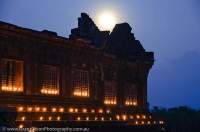 LAOS, Champasak. Ruined pavilions of middle level of Wat Phu, ancient Khmer religious complex, built between 10th & 16th centuries, lit by candle lanterns, with rising full moon.
