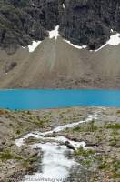 NORWAY, Troms, Lyngsalpan (Lyngen Alps). Blavatnet, water colour due to fine suspended glacial silt, and scree fans.