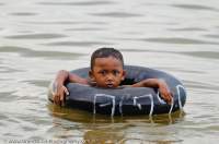 CAMBODIA, Siem Reap. Boy swimming with car inner tube float, Western Baray.