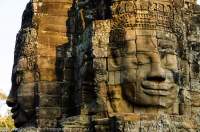 CAMBODIA, Siem Reap. Some of 216 carved stone faces at Bayon temple, built in late 12th century by Buddhist King Jayavarman V11 as centre of his capital of Angkor Thom. Sunset.