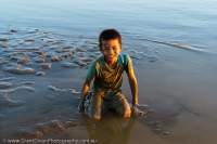 Boy playing in river shallows, Thanlwin River, sunset.