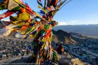 Buddhist prayer flags and Leh city, with barren mountain slopes of Indus valley beyond, from Namgyal Tsemo. Sunset.