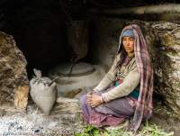 NEPAL, Mugu. Mugu woman grinding flour at water-driven grind stone.