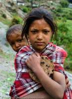 NEPAL, Mugu. Girl with baby and bread.