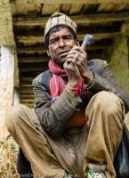 NEPAL, Mugu. Man relaxing with pipe.